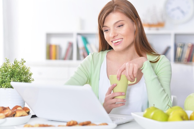 Foto retrato, de, hermoso, mujer joven, usar la computadora portátil, adentro