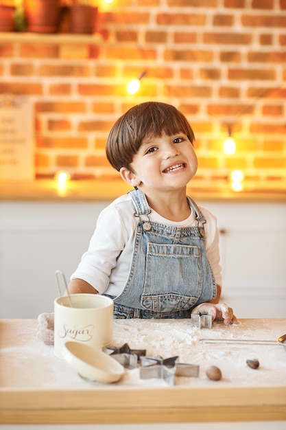 Un retrato de un hermoso niño aplaudiendo y sonriendo en la cocina