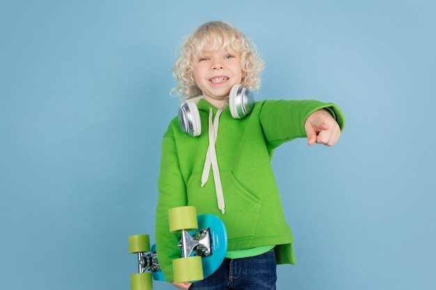 Retrato de hermoso niño caucásico aislado en la pared azul