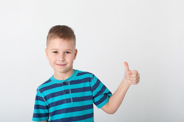 Retrato de un hermoso niño que te da el visto bueno sobre el fondo amarillo