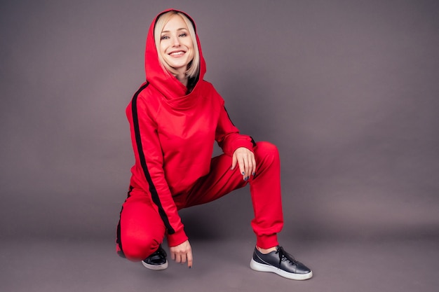 Retrato, de, un, hermoso, rubio, mujer, piel perfecta, y, maquillaje, puesto, en, capucha, sudadera con capucha, sudadera, chándal rojo, traje deportivo, bailarín de hip hop, en, estudio, en, negro, fondo., Bob, peinado corto, sensual, estilo