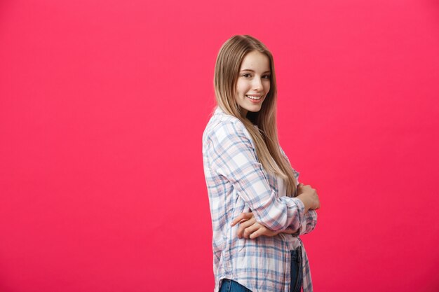 Retrato hermoso sonriente de la mujer con los brazos cruzados en fondo rosado