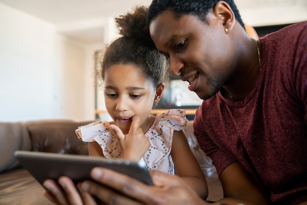 Retrato de una hija y un padre usando una tableta digital mientras se queda en casa