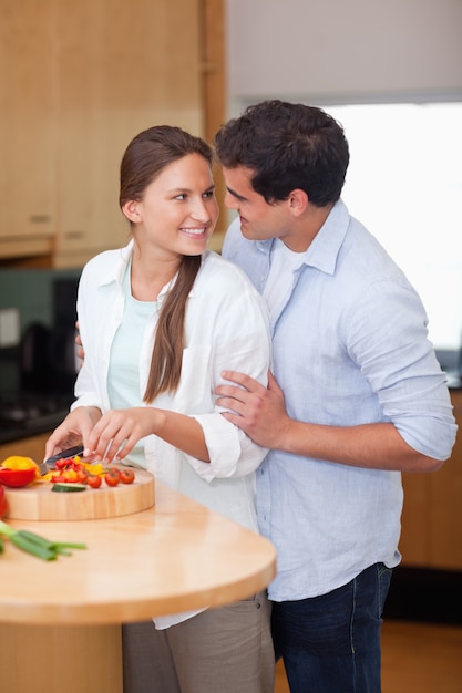 Retrato de un hombre abrazando a su esposa mientras ella está cocinando