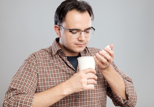 Retrato de un hombre abriendo y oliendo una taza de café sobre un fondo gris