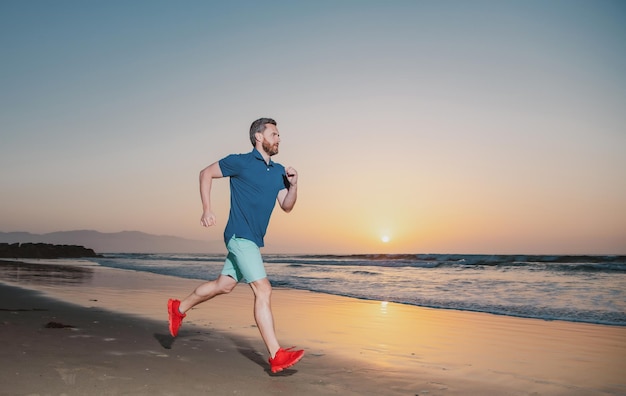 Retrato de un hombre activo de mediana edad trotando corriendo afuera por el mar