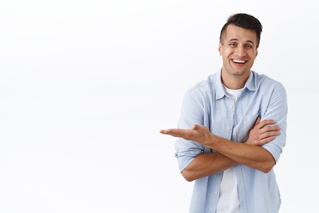 Retrato de un hombre adulto guapo que muestra la promoción del producto señalando con la mano a la izquierda el espacio vacío en blanco que presenta un anuncio que recomienda la tienda en línea del servicio de la empresa o el producto sonriendo complacido