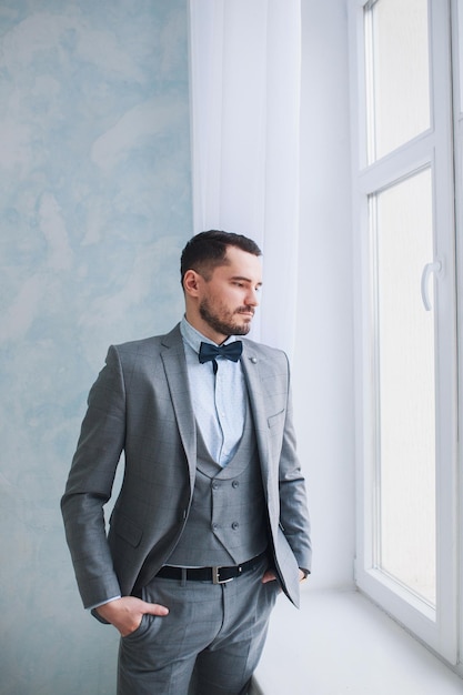 Retrato de un hombre guapo con un traje gris en el estudio el novio está esperando la novia boda Foto Premium