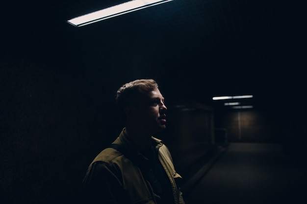 Retrato de hombre adulto joven en jeans verdes mirando hacia la luz.