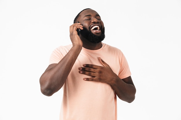 Retrato de un hombre africano casual feliz que se encuentran aisladas, hablando por teléfono móvil