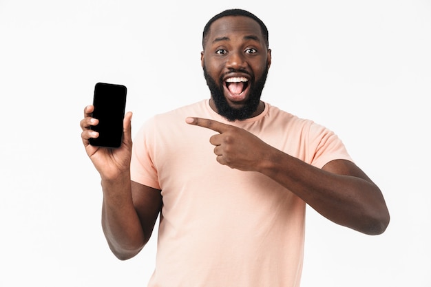 Retrato de un hombre africano casual feliz que se encuentran aisladas, mostrando el teléfono móvil de pantalla en blanco