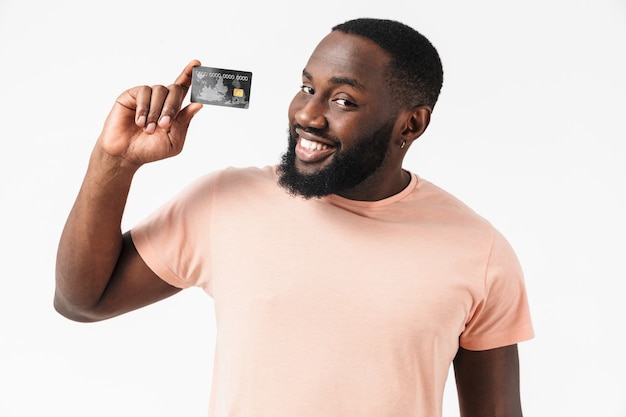 Retrato de un hombre africano confiado feliz con camisa que se encuentran aisladas, mostrando la tarjeta de crédito