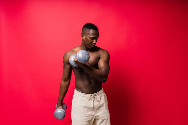 Foto retrato de un hombre africano feliz con pesas sobre fondo rojo y negro