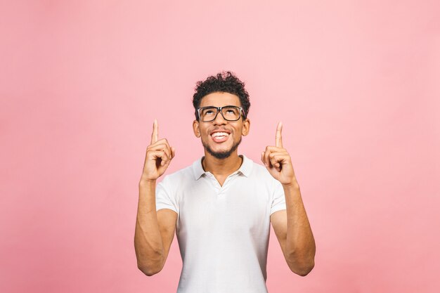 Retrato de un hombre africano feliz sonriente en señalar casual con los dedos para arriba aislado sobre fondo rosado.