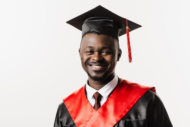 Retrato de un hombre africano graduado de la universidad y obtuvo un título de maestría Graduación Un hombre africano feliz con una túnica negra de graduación está sonriendo sobre fondo blanco