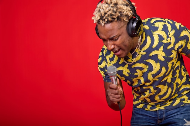 Retrato de un hombre africano hermoso disfrutando positivo con un micrófono y auriculares en la cabeza