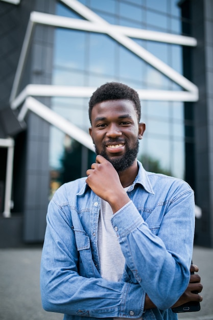 Retrato de hombre africano negro muy feliz, sonriendo en el fondo urbano