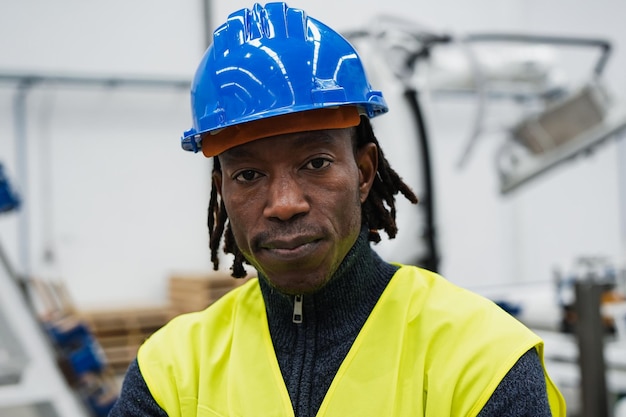 Retrato del hombre africano que trabaja dentro de la fábrica robótica