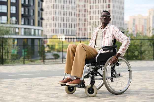 Retrato de un hombre afroamericano con discapacidad mirando la cámara mientras camina por la ciudad