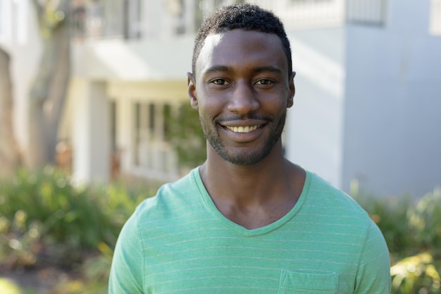 Retrato de un hombre afroamericano mirando la cámara y sonriendo en la soleada terraza del jardín. quedarse en casa aislado durante el bloqueo de cuarentena.