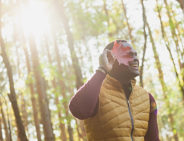 Retrato de hombre afroamericano que cubre su rostro con espacio de copia de hoja de arce otoñal Naturaleza otoñal Moda de otoño estacional