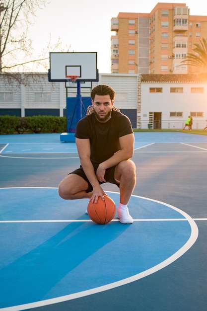 Retrato de un hombre afrolatino mirando a la cámara con una pelota en una cancha de baloncesto