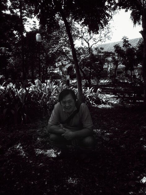 Foto retrato de un hombre agachado en un campo en un parque