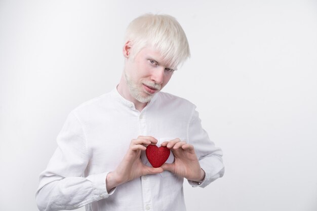 Retrato de un hombre albino sosteniendo un corazón