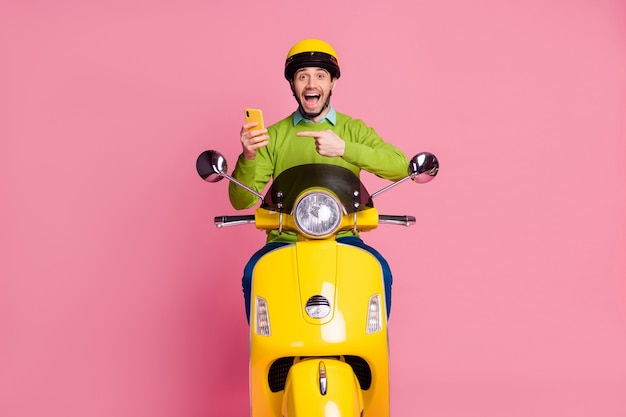 Retrato de hombre alegre montando moto mostrando el dedo directo celular