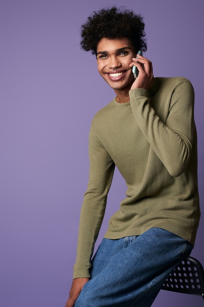 Retrato de hombre alegre morena hablando de móvil en camiseta casual