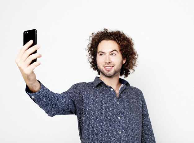 Retrato de un hombre alegre tomando selfie sobre fondo blanco.