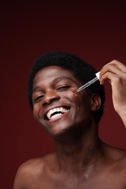 Foto retrato de un hombre aplicando suero facial y sonriendo