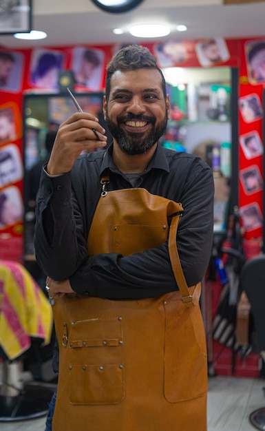 Retrato de hombre árabe peluquero feliz con tijeras