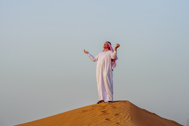 Retrato de hombre árabe sediento en medio del desierto amarillo.