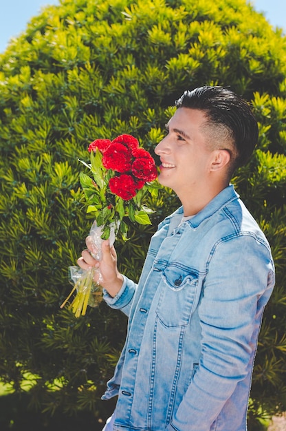 Retrato de un hombre argentino caucásico enamorado en un jardín oliendo un ramo de flores pensando en su novia y sonriendo