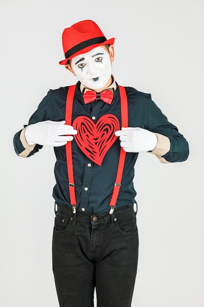 Retrato de un hombre artista payaso MIME muestra un corazón aislado sobre fondo blanco en Studio