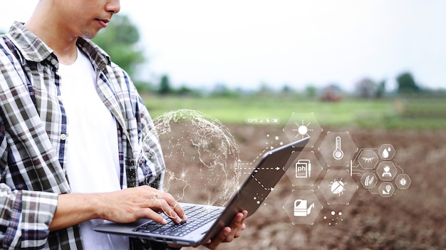 Retrato hombre asiático agricultor usando una computadora portátil digital en un campo de arroz agrícola en la mañana