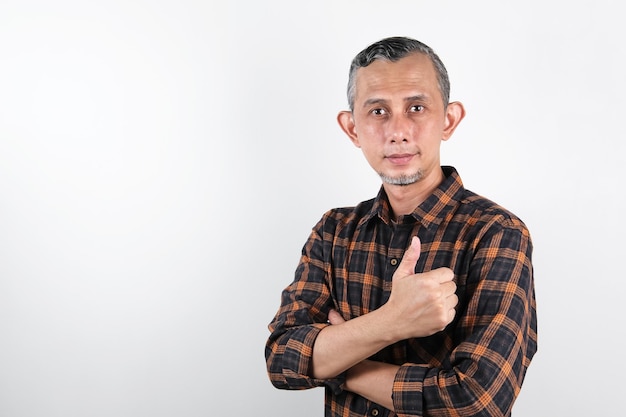 Retrato de un hombre asiático con camisa casual haciendo un gesto positivo con los pulgares hacia arriba