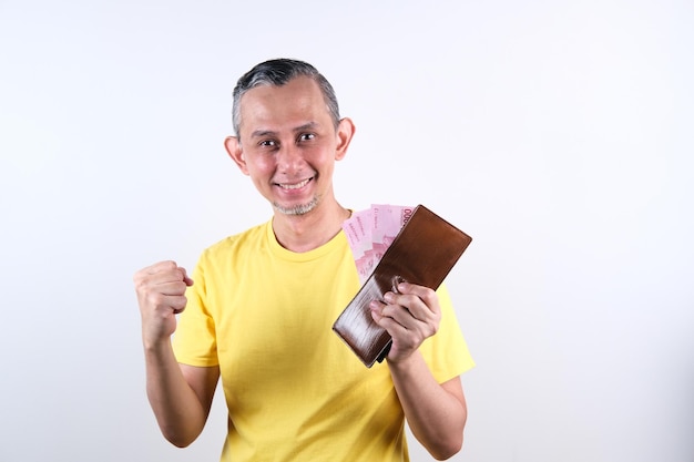 Retrato de un hombre asiático con camisa informal que se ve feliz con mucho dinero en la mano