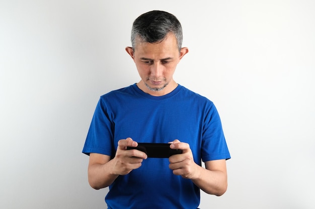 Retrato de un hombre asiático con camiseta azul parece serio con el teléfono