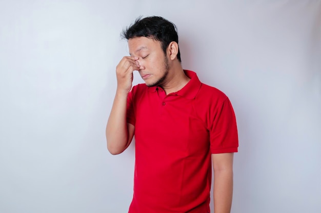 Un retrato de un hombre asiático con una camiseta roja aislado por un fondo blanco parece deprimido