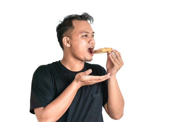Retrato de un hombre asiático disfrutando de una rebanada de pizza con una camiseta negra