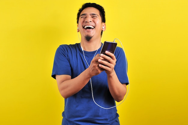 Retrato de hombre asiático emocionado sorprendido al encontrar una canción de tendencia en línea