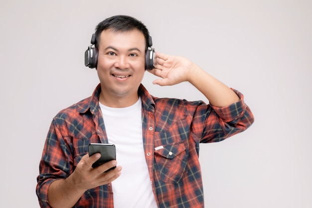 Retrato de hombre asiático escuchando una canción o música de auriculares negros.