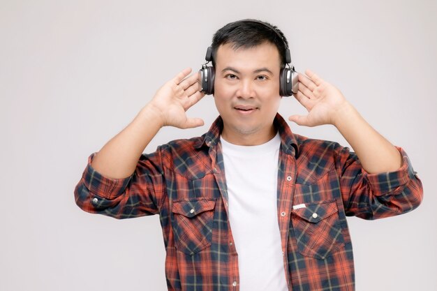 Retrato de hombre asiático escuchando una canción o música de auriculares negros.