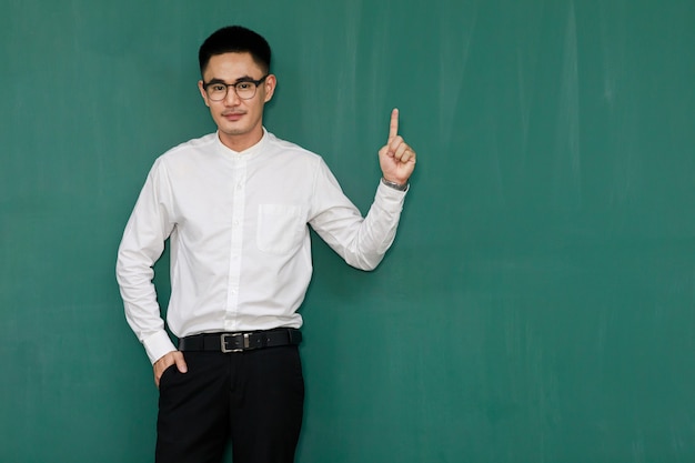 Retrato de hombre asiático joven y guapo con anteojos y ropa casual de negocios, camisa blanca y pantalón negro, posa en gestos publicitarios y presenta algo con confianza en sí mismo.