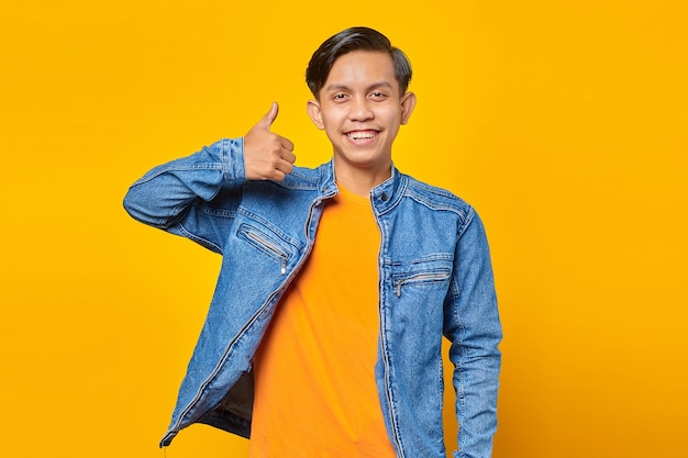 Retrato de hombre asiático joven sonriente y alegre que muestra los pulgares para arriba o el signo de aprobación