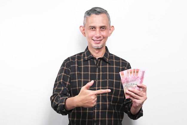 Retrato de un hombre asiático con un pantalones casual con mucho dinero en la mano (billetes indonesios)