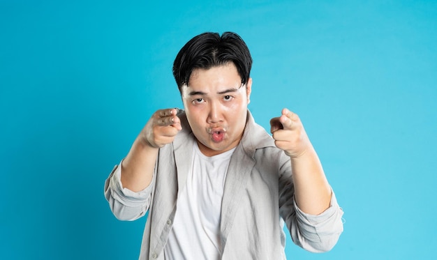 Retrato de un hombre asiático posando sobre un fondo azul
