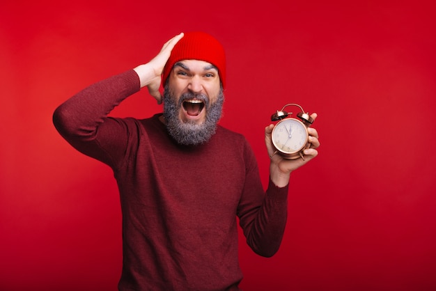 Retrato de hombre asombrado con barba blanca con despertador